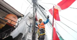 Petugas PLN sedang merapikan bendera dekorasi 17an yang menempel dengan jaringan listrik. Pemasangan seperti ini berisiko tinggi dan tidak aman. (Sumber: Dok. PLN UID Jakarta Raya)