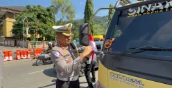 Dirlantas Polda Papua, Kombes Pol Tri Yulianto, membagikan dan langsung memasangkan bendera merah putih kepada supir truk barang di depan kantor Mapolda Papua. (Sumber: Ditlantas Polda Papua)