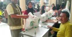 Lurah Kalibaru, Nayadih, membagikan beras bantuan pemerintah kepada warga penerima manfaat. (Sumber: Poskota/Angga Pahlevi)