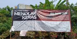Spanduk petisi penolakan kegiatan keagamaan Umi Cinta yang diduga menyimpang oleh warga Perumahan Dukuh Zamrud, Mustikajaya, Kota Bekasi terbentang lebar di depan rumah Umi Cinta. (Sumber: POSKOTA | Foto: Nurpini Aulia Rapika)