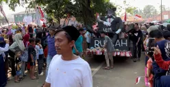 Peserta karnaval 17 Agustus 2025 di Kecamatan Menes, Pandeglang, membawa ornamen tikus berdasi ukuran besar. (Sumber: POSKOTA | Foto: Samsul Fatoni)