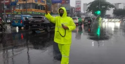 Kanit Turjawali Satlantas Polres Metro Depok, AKP Fitri (mengenakan jas hujan) mengatur lalu lintas di Jalan Margonda, saat hujan deras yang menyebabkan kemacetan, Selasa, 19 Agustus 2025. (Sumber: Poskota/Angga Pahlevi)