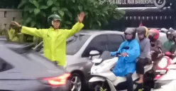 Seorang polisi mengenakan jas hujan mengatur arus lalu lintas di Jalan Raya Cinere, Depok, saat hujan deras yang menyebabkan kemacetan pada Selasa, 19 Agustus 2025). (Sumber: Poskota/Angga Pahlevi)