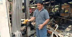 Asep, salah satu pedagang Pasar Pejuang Pratama, mengais buah jeruk miliknya yang tersisa di antara puing dan arang bekas kebakaran, Minggu 24 Agustus 2025. (Sumber: POSKOTA | Foto: Nurpini Aulia Rapika)