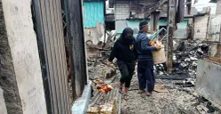 Pedagang Pasar Pejuang Pratama mengais sisa dagangan yang masih bisa diselamatkan usai kios mereka ludes terbakar, Sabtu malam, 23 Agustus 2025. (Sumber: POSKOTA | Foto: Nurpini Aulia Rapika)