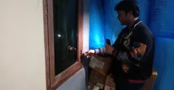 Pegawai toko online, Aldo, menunjukkan jendela yang dirusak maling untuk melancarkan malingnya, Senin 25 Agustus 2025. (Sumber: POSKOTA | Foto: Giffar Rivana)