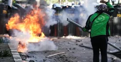 Seorang massa aksi berpakaian ojol menantang pihak keamanan dalam demonstrasi di depan Mako Brimob Polda Metro Jaya, Kwitang, Jakarta Pusat, Jumat, 29. Agustus 2025. (Sumber: Poskota/Bilal Nugraha Ginanjar)