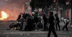 Massa aksi berlindung di balik tameng saat bentrok dengan pihak keamanan di Satuan Brimob Polda Metro Jaya, Kecamatan Senen, Jakarta Pusat, Jumat, 29 Agustus 2025. (Sumber: Poskota/Bilal Nugraha Ginanjar)