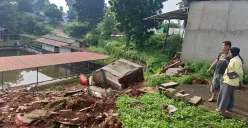 Warga melihat kondisi tebing pembatas Perumahan SIK di Kelurahan Kedaung, Sawangan, Depok, yang longsor akibat luapan air Setu Tujuh Muara setelah hujan deras, Kamis, 11 Desember 2025. (Sumber: Poskota/Angga Pahlevi)