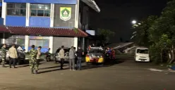 Sejumlah petugas polisi dan TNI berjaga pascapenemuan sesosok mayat pria di Gedung KNPI Cibinong, Minggu, 14 Desember 2025. (Sumber: POSKOTA | Foto: Giffar Rivana)