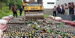 Kapolres Cimahi, AKBP Niko N Adi Putra (tengah), menggilas ribuan botol minuman beralkohol menggunakan alat berat, di Lapangan BPKB Mapolres Cimahi, Jumat 19 Desember 2025. (Sumber: Poskota | Foto: Gatot Poedji Utomo)