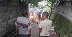 Heri (kanan) bersama warga sedang melihat jalan yang amblas di lingkungan mereka sedang diperbaiki oleh Dinas PUPR Kota Depok, Jumat siang, 14 Februari 2025. (Sumber: Poskota/Angga Pahlevi)