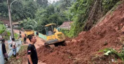 Petugas BPBD KBB dan warga berjibaku membersihkan material longsor di Jalan Raya Kampung Tugu RW 14 Desa Ciharashas, Kecamatan Cipeundeuy, Rabu 26 Februari 2025. (Sumber: Poskota/Gatot Poedji Utomo)