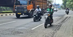 Pengendara motor terlihat hati-hati saat melintas di Jalan Ahmad Yani, Kota  Bekasi dengan kondisi hamparan pasir dan penambalan lubang jalan. Sabtu, 11 Desember 2025. (Sumber: Poskota/Ihsan)