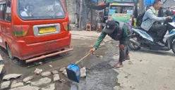 Warga hendak membersihkan genangan air yang selalu terjadi di area Stasiun Bekasi menuju Kampung Pintu, Jalan Raya Perjuangan, Bekasi Utara, Kota Bekasi, Rabu, 22 Januari 2025. (Sumber: Poskota/Ihsan Fahmi)