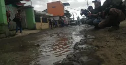 Warga Desa Wangunharja, Kecamatan Lembang, Kabupaten Bandung Barat memancing di tengah jalan yang tergenang air sebagai aksi protes akibat jalan rusak. (Sumber: Poskota/Gatot Poedji Utomo)