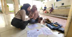 Diah (kanan) menangis sambil mengeringkan ijazah anaknya yang terendam banjir di pengungsian Masjid An Nur, Cengkareng, Jakarta Barat, Jumat, 31 Januari 2025. (Sumber: Poskota/Pandi Ramedhan)