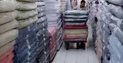 Pekerja Focus Textile mendorong tumpukan kain yang dikemas rapi di salah satu gudang. Industri tekstil tetap beroperasi di tengah tekanan ekonomi dan persaingan impor. (Sumber: Istimewa)