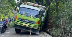 Truk Hino berwarna hijau-putih terperosok ke parit setelah gagal menanjak di Tanjakan Parakan, Pamulang, Tangerang Selatan, pada Jumat, 4 Juli 2025. (Sumber: Poskota/Primayanti Juli Kumala Manalu)