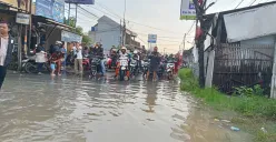 Jalan Raya Pisangan, Desa Satria Mekar, Kecamatan Tambun Utara, Kabupaten Bekasi, lumpuh total usai terendam banjir setinggi 50 sentimeter. Selasa, 8 Juli 2025. (Sumber: Poskota/Nurpini Aulia Rapika)