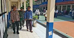Anggota Bhabinkamtibmas Kelurahan Gandul, Kota Depok, bersama Babinsa melakukan pengamanan pendaftaran SPMB 2025. (Sumber: POSKOTA | Foto: Angga Pahlevi)