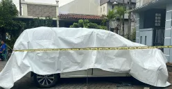 Kondisi mobil milik korban M yang tewas terbakar dipasang garis polisi di Perumahan Graha Pondok Kacang, Tangerang Selatan pada Selasa, 3 Juni 2025. (Sumber: POSKOTA | Foto: Primayanti)