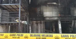 Garis polisi melintang di gudang ban Jalan Raya Jatimakmur, Pondok Gede, Kota Bekasi, yang ludes terbakar pada malam takbiran Idul Adha, Kamis 5 Juni 2025. (Sumber: Poskota/Nurpini Aulia Rapika)