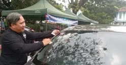 Petugas DLH Kota Cimahi memasang stiker tanda lolos uji emisi pada kendaraan. (Sumber: POSKOTA | Foto: Gatot Poedji Utomo)