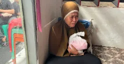 Nurjanah, 49 tahun, orangtua korban kebakaran rumah tinggal di Tebet, Jaksel, sedang menggendog buntelan plastik berisikan bagian tubuh anaknya yang terbakar, Kamis, 19 Juni 2025. (Sumber: Poskota/Pandi Ramedhan)