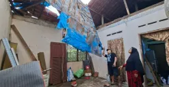 Oma Endah didampingi Ketua RT menujukkan atap yang ambruk tidak tersisa hanya ada sisa terpal untuk menahan air dari banjir di Kota Depok, Jumat, 20 Juni 2025. (Sumber: Poskota/Angga Pahlevi)