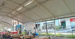 Suasana di area kuliner untuk UMKM yang berlokasi di luar sebuah pusat perbelanjaan, Grand Mall Bekasi. Deretan meja dan bangku kayu terlihat kosong, menanti kedatangan pengunjung di bawah naungan tenda. (Sumber: Poskota/Nurpini Aulia Rapika)