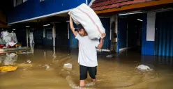 Warga membawa karung berisi dagangan saat banjir di pasar Cipulir, Jakarta Selatan, Selasa, 4 Maret 2025. (Sumber: Poskota/Bilal Nugraha Ginanjar)