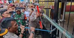 Petugas Satpol PP Kota Depok menggunakan linggis untuk membongkar paksa rantai yang mengunci gerbang SDN Utan Jaya, Cipayung, Kota Depok, Kamis, 8 Mei 2025. (Sumber: Poskota/Angga Pahlevi)