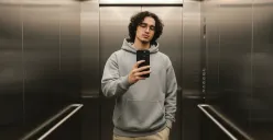 Hasil edit prompt Gemini AI foto cowok mirror selfie pakai iPhone 17 Pro Max di lift yang ganteng maksimal. (Sumber: Freepik/user18526052)