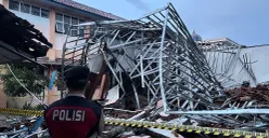 Petugas polisi berjaga di SMKN 1 Gunung Putri yang ambruk akibat hujan deras dan angin kencang yang melanda wilayah tersebut. (Sumber: POSKOTA | Foto: Giffar Rivana)