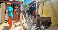 Petugas PPSU membantu membersihkan bangunan warga yang rusak akibat tanah amblas di GG Sumur Jambu, Kelurahan/Kecamatan Makasar, Jaktim. (Sumber: POSKOTA | Foto: M Tegar Jihad)