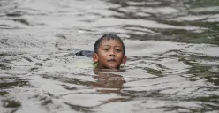 Seorang anak berenang pada genangan banjir di Jakarta. (Sumber: Poskota/Bilal Nugraha Ginanjar)
