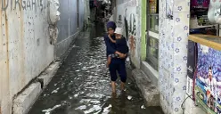 Warga melintasi genangan air akibat banjir rob di RW 22 Kelurahan Muara Angke, Kecamatan Penjaringan, Jakarta Utara pada Sabtu, 22 November 2025. (Sumber: POSKOTA | Foto: Pandi Ramedhan)