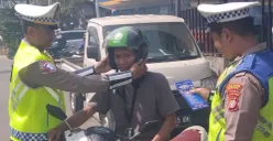 Kanit Lantas Polsek Cinere, Iptu Suharyoko memasangkan helm kepada pengendara saat Operasi Zebra Jaya 2025. (Sumber: Dok. Polsek Cinere)