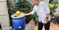 Joko, Ketua RT 08/RW 018, menunjukkan air bantuan dari distribusi PDAM Tirta Patriot yang ia tampung di galon hingga gentong di halaman rumahnya. (Sumber: POSKOTA | Foto: Nurpini Aulia Rapika)