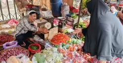 Hasanudin, pedagang sayur di Pasar Baru Bekasi Timur sedang melayani pembeli di lapaknya, Selasa, 7 Oktober 2025. (Sumber: POSKOTA | Foto: Nurpini Aulia Rapika)