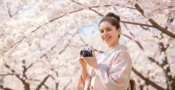 Hasil edit prompt Gemini AI terbaru edit foto wanita liburan di Jepang dengan view bunga sakura. (Sumber: Freepik/user18526052)