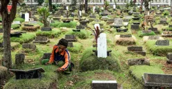 Petugas sedang membersihkan rumput di TPU Grogol Selatan, Kecamatan Kebayoran Lama, Jakarta Selatan. (Sumber: POSKOTA | Foto: Bilal Nugraha Ginanjar)