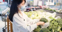 Seorang ibu tengah memilih sayuran di pasar tradisional dengan cermat. (Sumber: Pinterest)