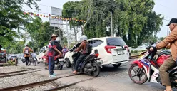 Suasana pelintasan kereta Bulak Kapal, Bekasi Timur, tanpa palang pintu di kedua sisinya. Petugas bersama warga mengatur lalu lintas yang padat, Minggu 14 September 2025. (Sumber: POSKOTA | Foto: Nurpini Aulia Rapika)