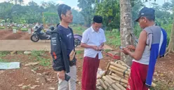 Ketua lingkungan RT 04 RW 04, Herman alias Gareng, (kopiah hitam) bersama warga mencoba mencari informasi ke penggali makam terkait kebenaran informasi viral di TPU Pasir Putih. (Sumber: Poskota/ Angga Pahlevi)