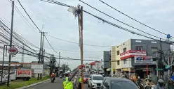 Kabel menjuntai ke jalan raya di Depok ditopang bambu dan kayu. (Sumber: Poskota/ Angga Pahlevi)
