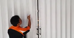 Pegawai toko menunjukkan pintu teralis besi yang dibobol pelaku. (Sumber: Istimewa)