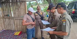 Anggota Satpol PP Kabupaten Tangerang mengirimkan surat peringatan kepada pemilik bangunan liar di Jalan Raya Pakuhaji, Desa Keramat, Kecamatan Pakuhaji, Kabupaten Tangerang. (Sumber: Poskota/Veronica Prasetio)