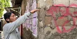 Yudi warga RW 05 Kelurahan Rawa Terate, Jakarta Timur sambil menunjuk bekas batas air di dinding rumahnya, Senin, 19 Januari 2026. (Sumber: Poskota/M Tegar Jihad)